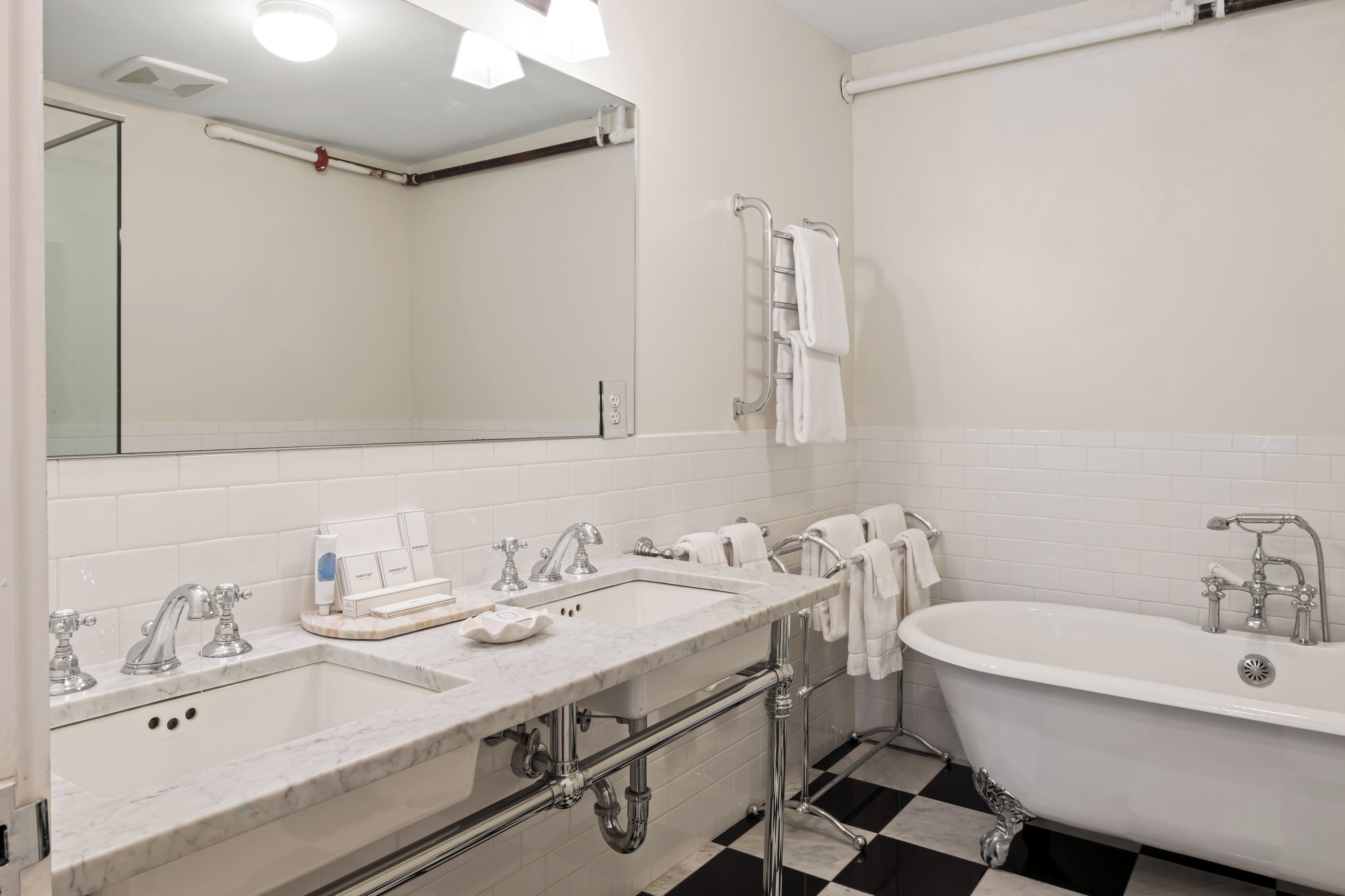 Baño con lavamanos doble, bañera y espejo.