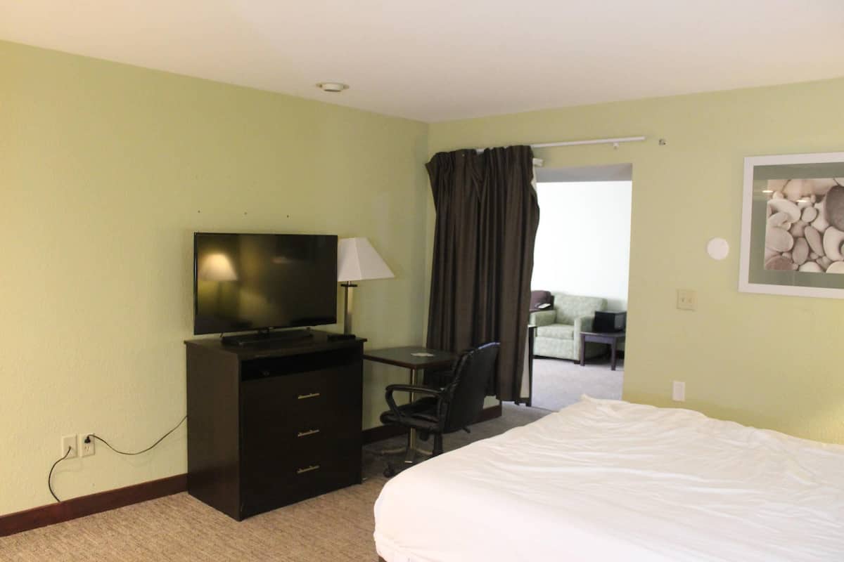 A hotel room with a bed, a desk with a chair, a television, and a lamp.