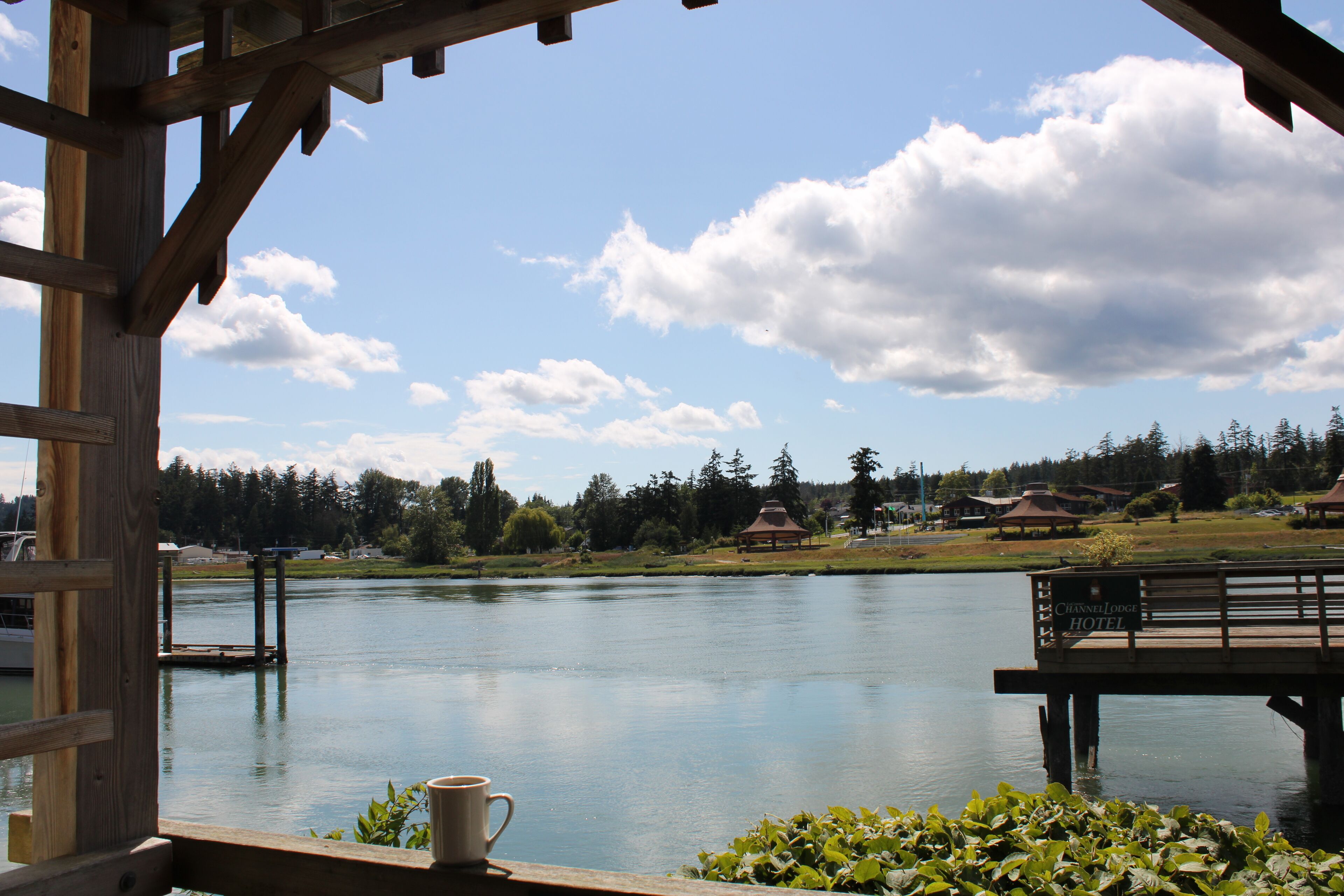 A wooden deck overlooking a calm lake with a gazebo and a sign for the Channel Lodge Hotel.