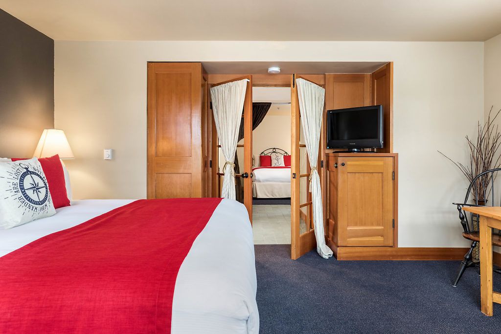 Ein Hotelzimmer mit Bett, Fernseher, Schreibtisch und Stuhl.