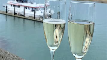 Two glasses of white wine on a wooden surface with a body of water and a boat in the background.