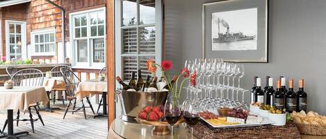 A table set for a wine tasting event with bottles, glasses, and various cheeses and fruits.