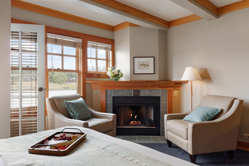 Una habitación acogedora con chimenea, dos sillones, una cama y una bandeja de comida.