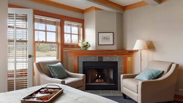 Una habitación acogedora con chimenea, dos sillones, una cama y una bandeja de comida.