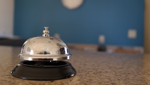 Ein Hotelzimmer mit einer schwarzen und silbernen Türklingel, einer Wanduhr und einer Arbeitsplatte aus Granit.
