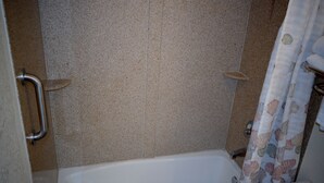 Ein Badezimmer mit Badewanne, Duschvorhang und Handlauf.