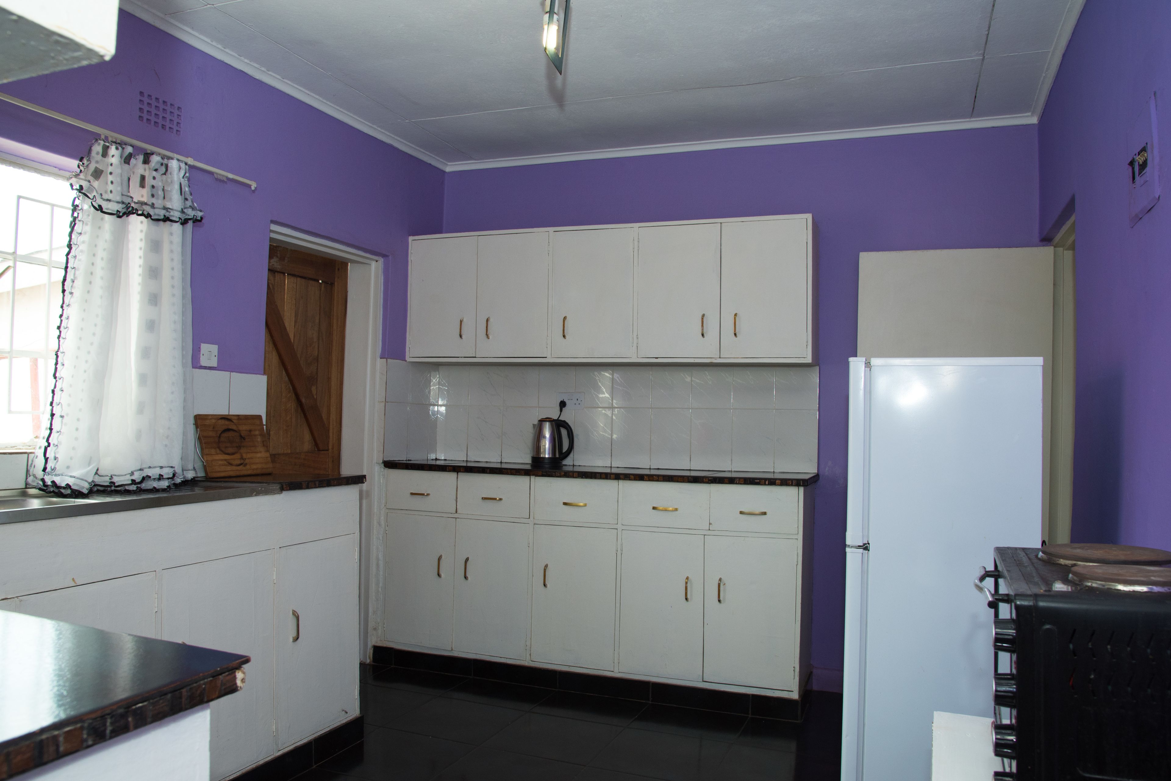 Una cocina con armarios blancos, un refrigerador y una cafetera sobre la encimera.