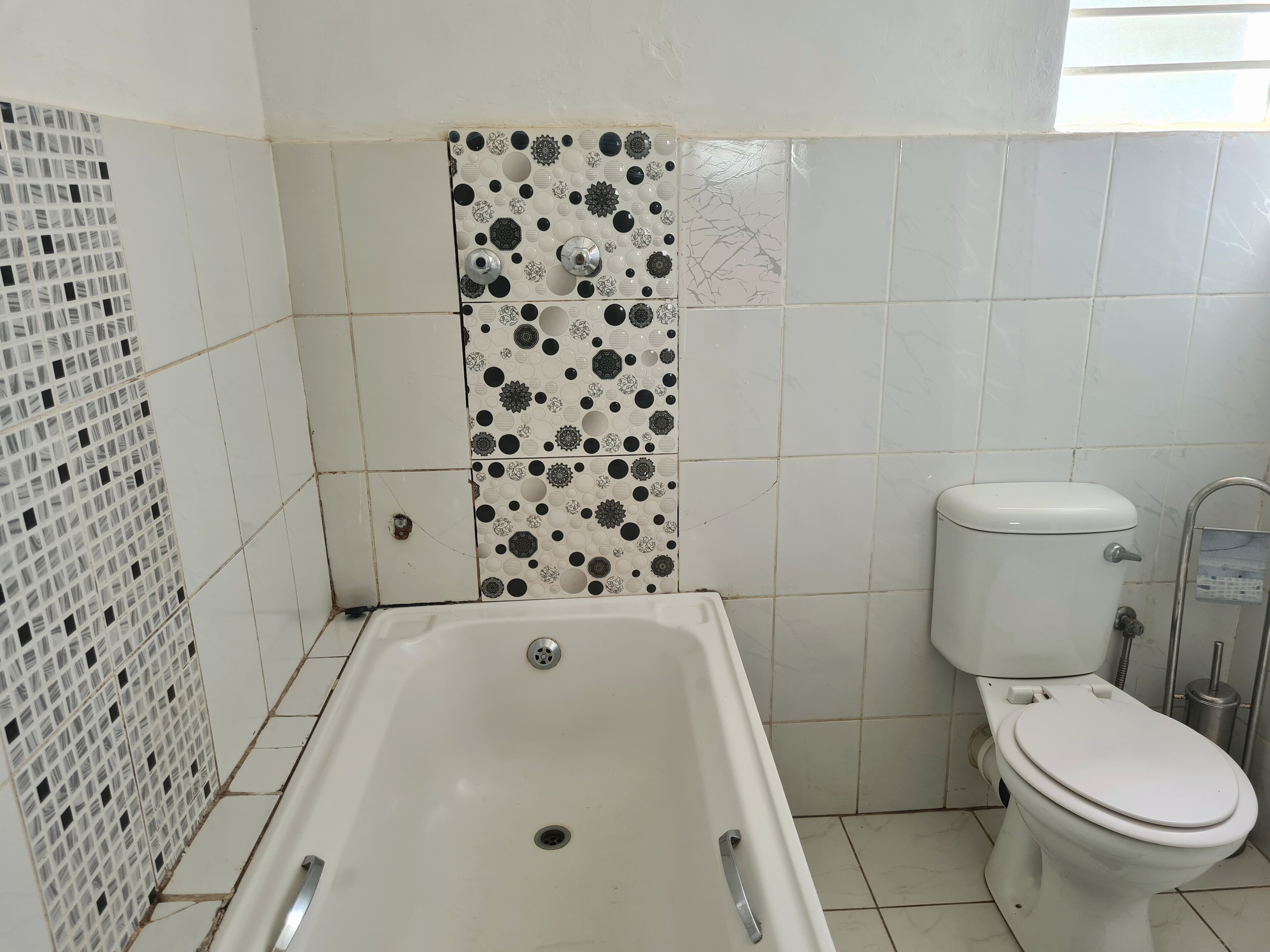 A bathroom with a bathtub, toilet, and decorative tiles.