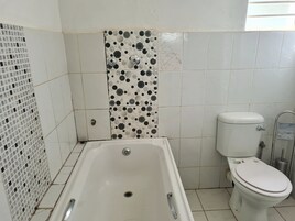 Un baño con bañera, inodoro y azulejos decorativos.