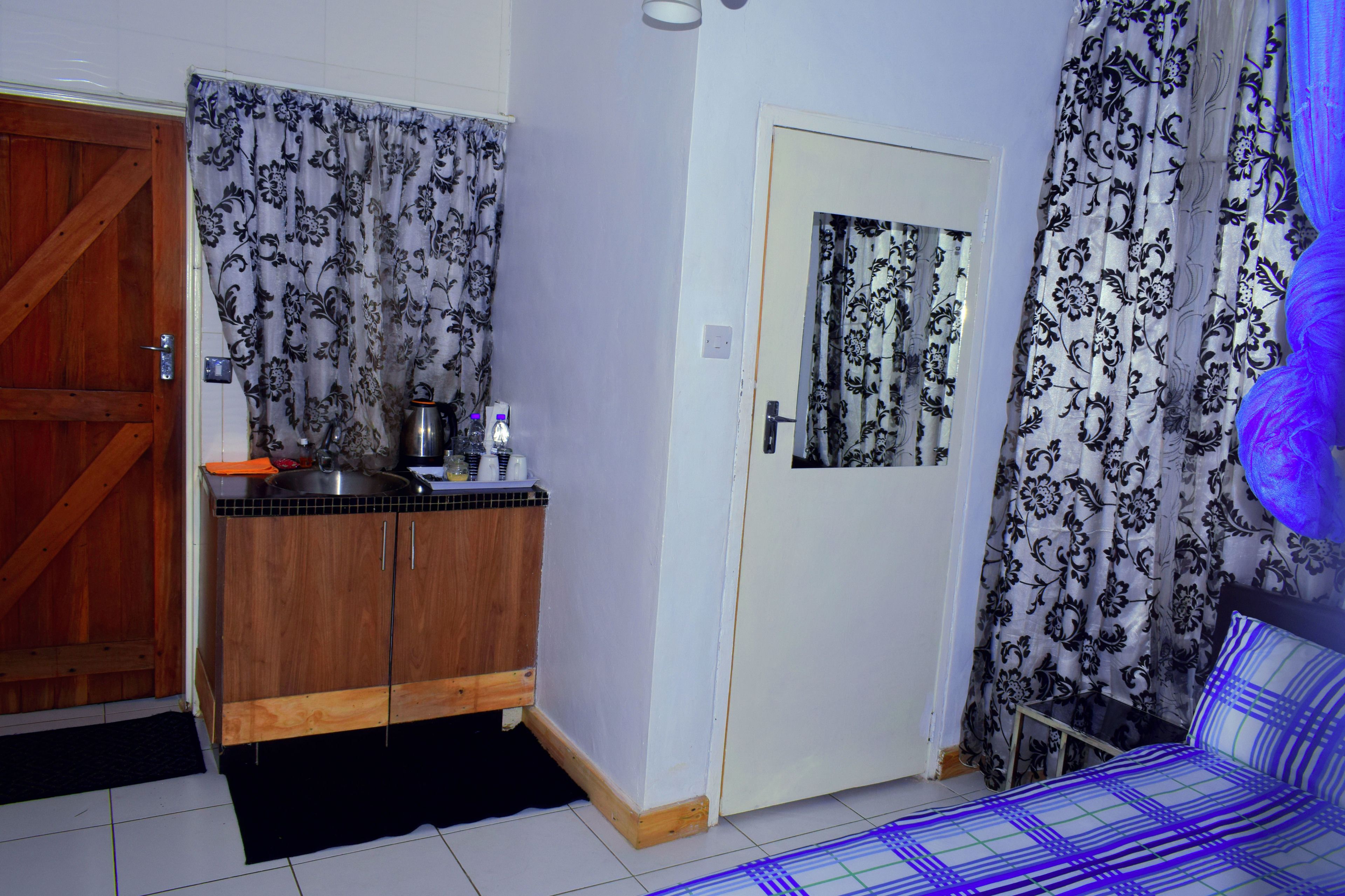 A compact room with a kitchenette, a bed, and a door leading to another room.