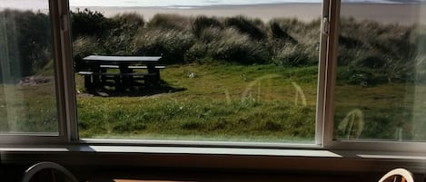 Una habitación con un ventanal grande con vista a una playa y una mesa de picnic.
