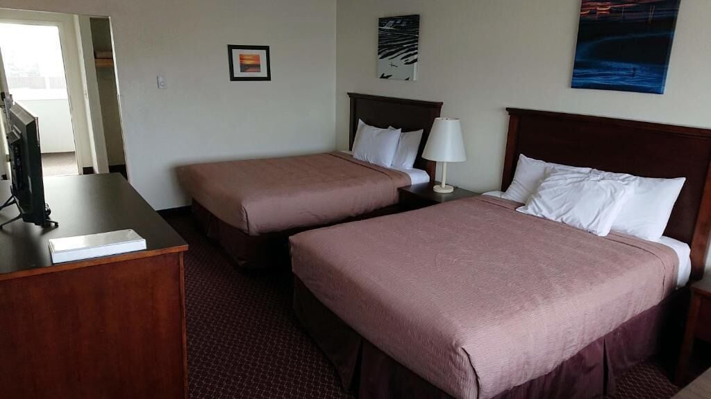 Une chambre d’hôtel avec deux lits, un bureau et une télévision.