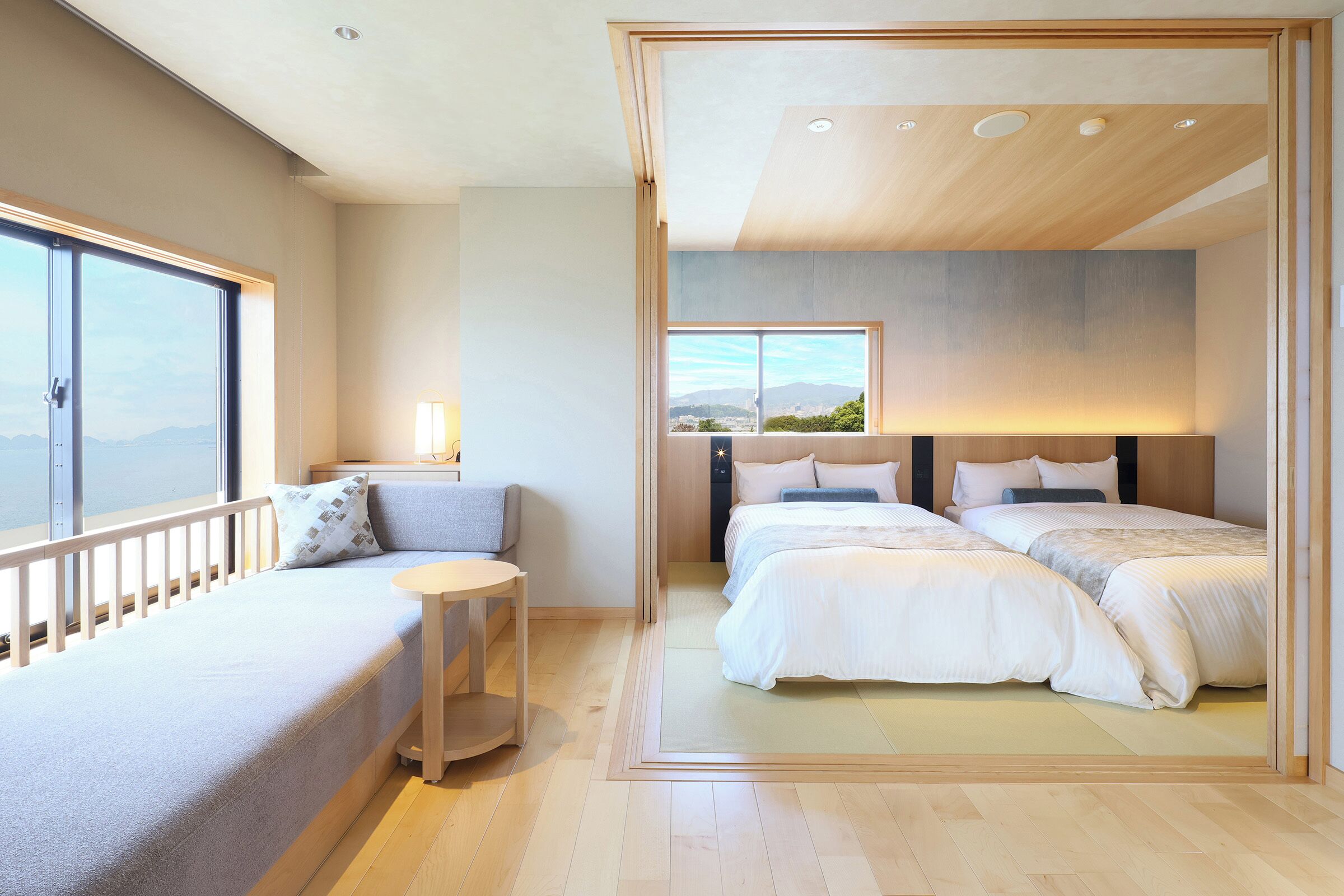 A modern bedroom with a large window, a sofa, and two beds.
