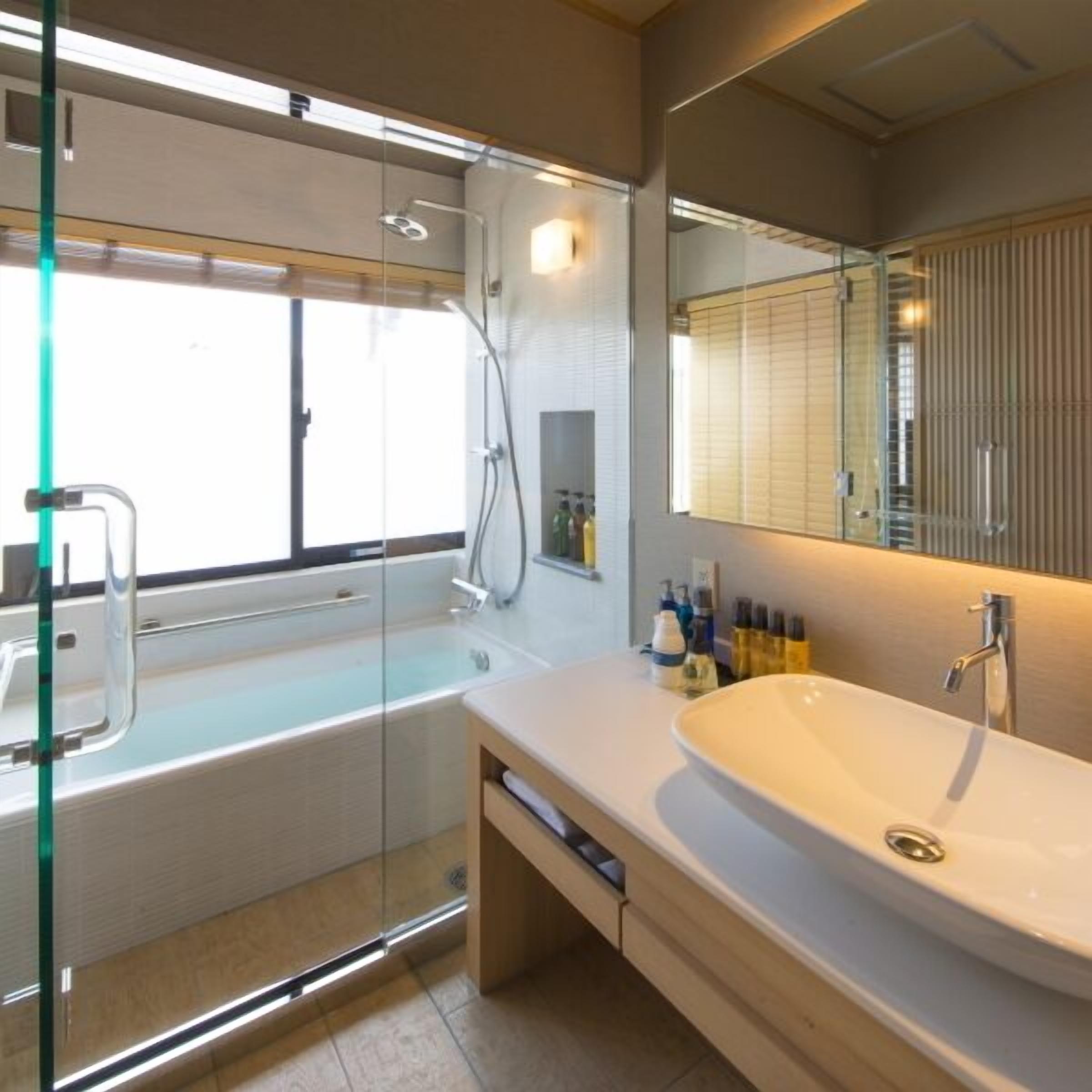 A modern bathroom with a glass-enclosed shower, a freestanding bathtub, and a large sink with a mirror above it.