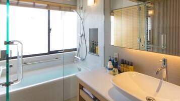 A modern bathroom with a glass-enclosed shower, a freestanding bathtub, and a large sink with a mirror above it.