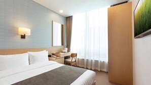 A hotel room with a large bed, a desk, a chair, a desk lamp, and a window with sheer curtains. - Migliore Hotel Seoul Myeongdong (Seoul)