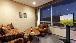 A hotel room with a large window, two sofas, a small table, and a flat-screen TV displaying a cityscape. - Migliore Hotel Seoul Myeongdong (Seoul)