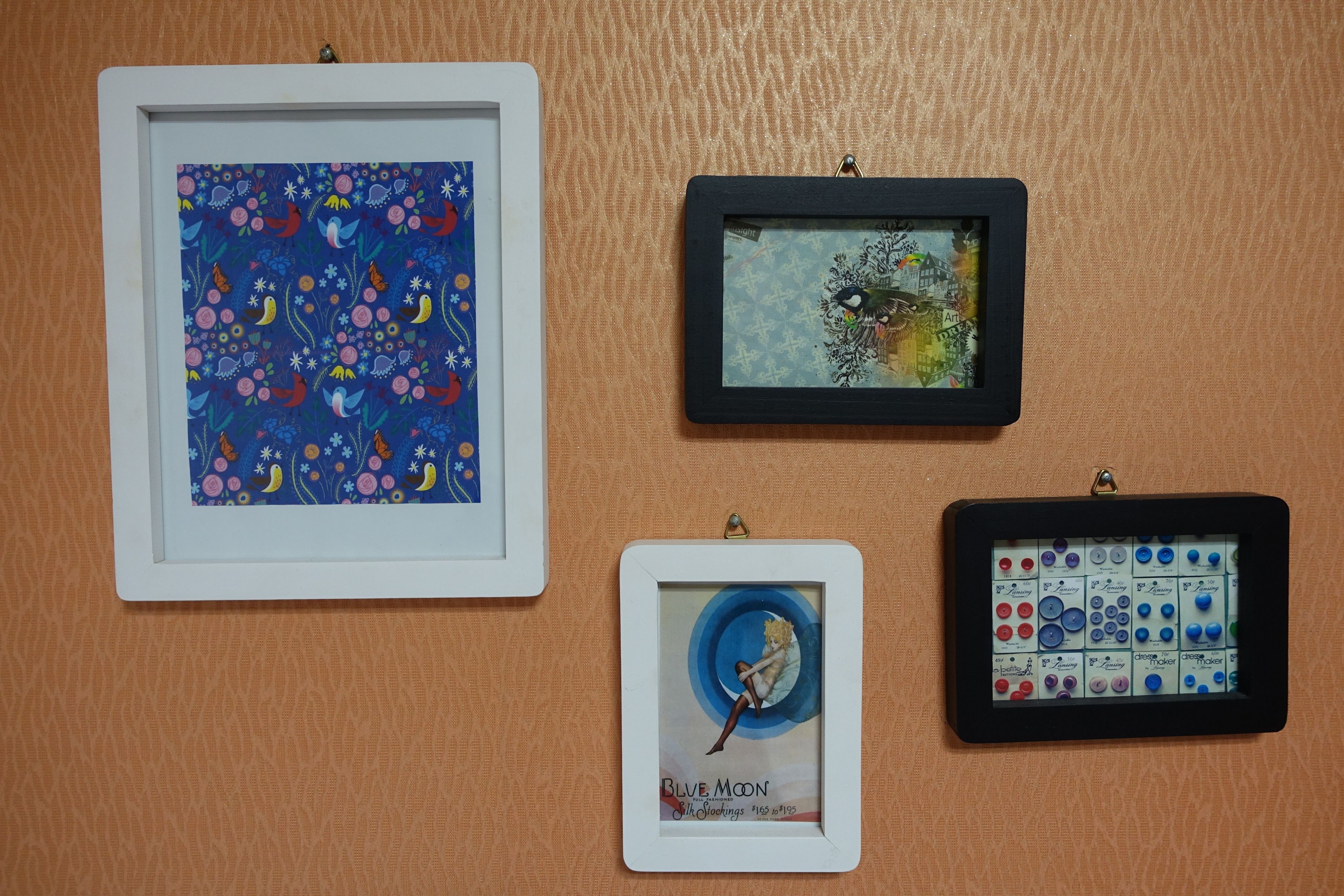 Four framed artworks on a textured wall.
