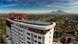 Hotel Indolux met een dakterraszwembad, omgeven door een stadsgezicht en een berg op de achtergrond.