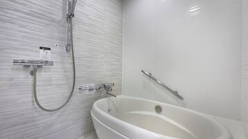 Un baño moderno con una bañera independiente, un cabezal de ducha manual y una barra de apoyo de seguridad.