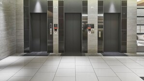 A modern elevator with a digital display, a fire alarm button, and a wheelchair accessibility sign.
