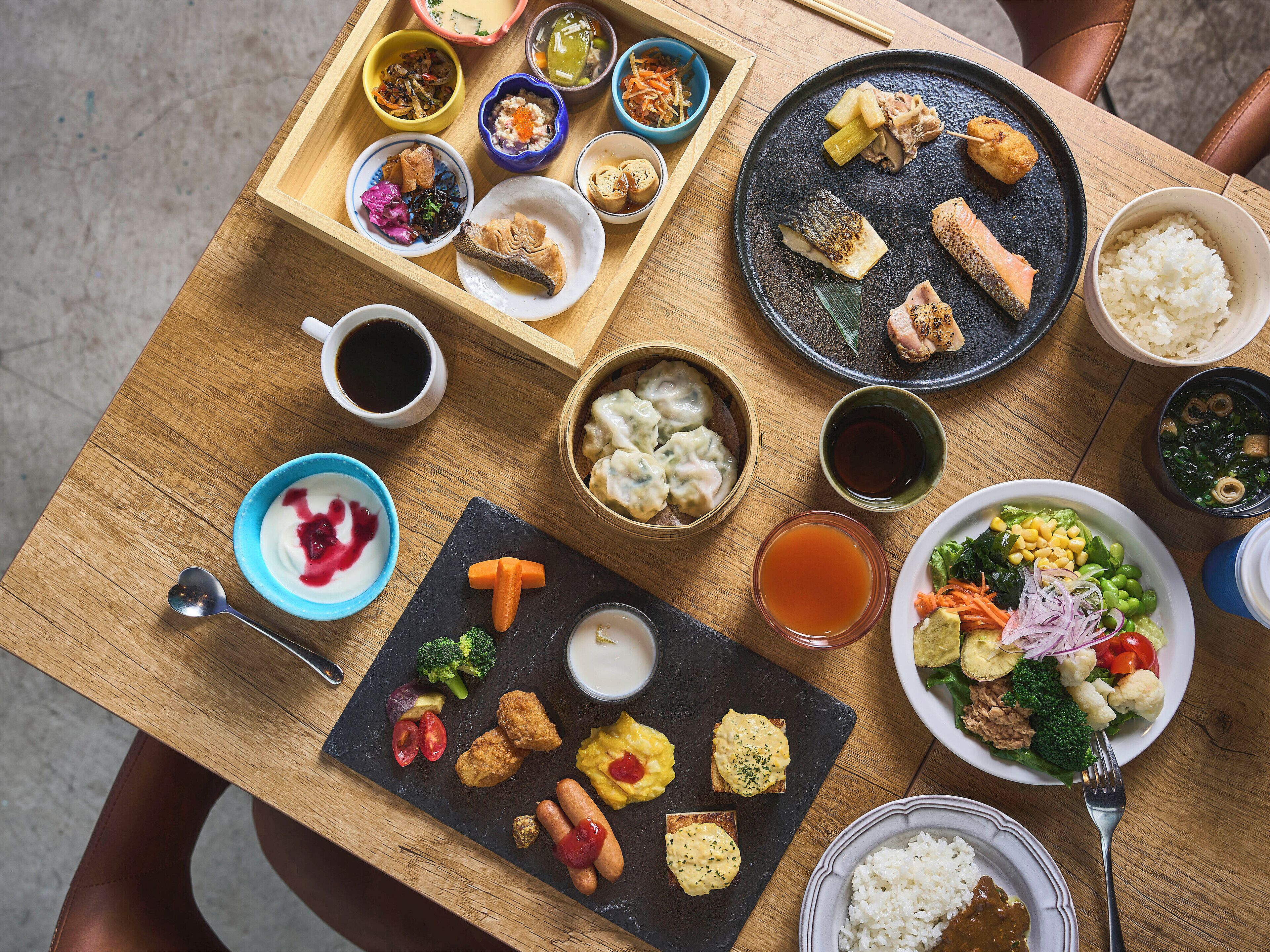 Uma mesa de madeira com diversos pratos, incluindo sushi, dumplings e uma salada.