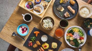 Uma mesa de madeira com diversos pratos, incluindo sushi, dumplings e uma salada.