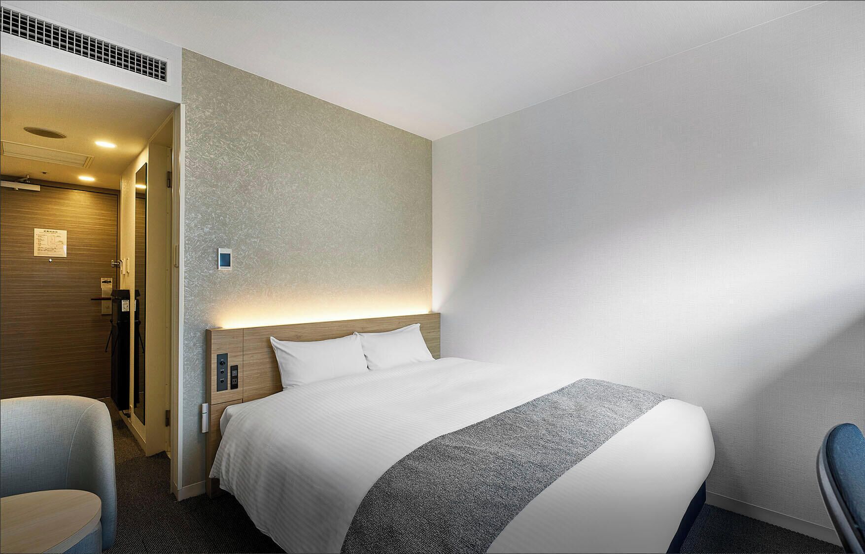Una habitación de hotel con cama, escritorio, silla y zona de ducha.