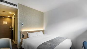 Una habitación de hotel con cama, escritorio, silla y zona de ducha.