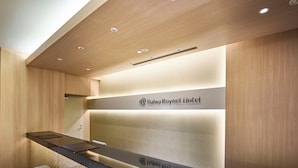 A reception desk with a wooden finish and a sign for Daiwa Roynet Hotel.