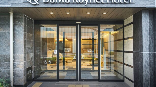 The Daiwa Roynet Hotel entrance with glass doors and a sign above.