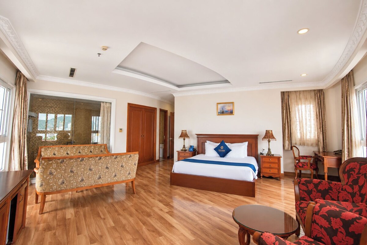 Een hotelkamer met een bed, een bank, een eettafel en een stoel.