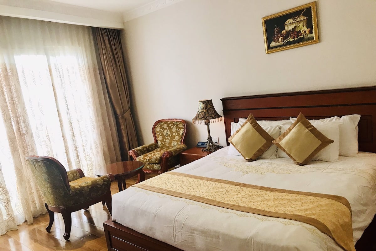 Ein Hotelzimmer mit einem großen Bett, einem Sessel, einem kleinen Tisch und einer Lampe.