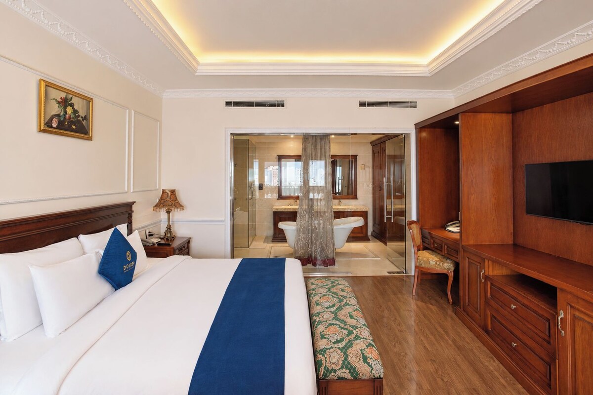 Een hotelkamer met een groot bed, een bureau, een televisie en een badkamer zichtbaar door een geopende deur.