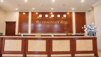 A reception desk at NHA TRANG PALACE HOTEL with clocks displaying time in London, New York, Ha Noi, Tokyo, and Moscow.