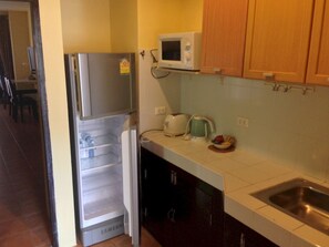 A kitchen with a stainless steel refrigerator, a microwave, a kettle, and a sink. - Nin Apartments Karon Beach (Karon)