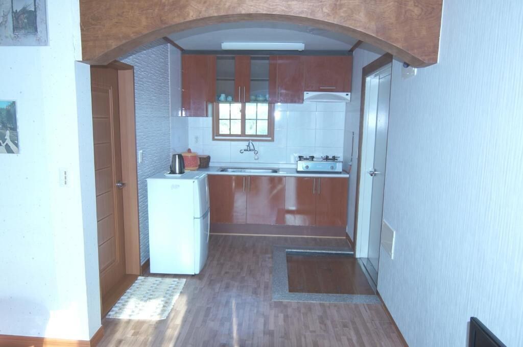 Eine kleine Küche mit Holzschränken, einem weißen Kühlschrank und einem Gasherd.
