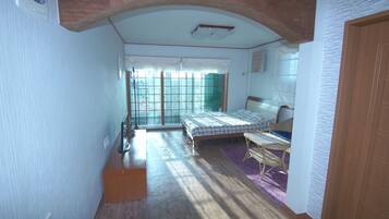 A bedroom with a bed, a chair, a window, and a door.