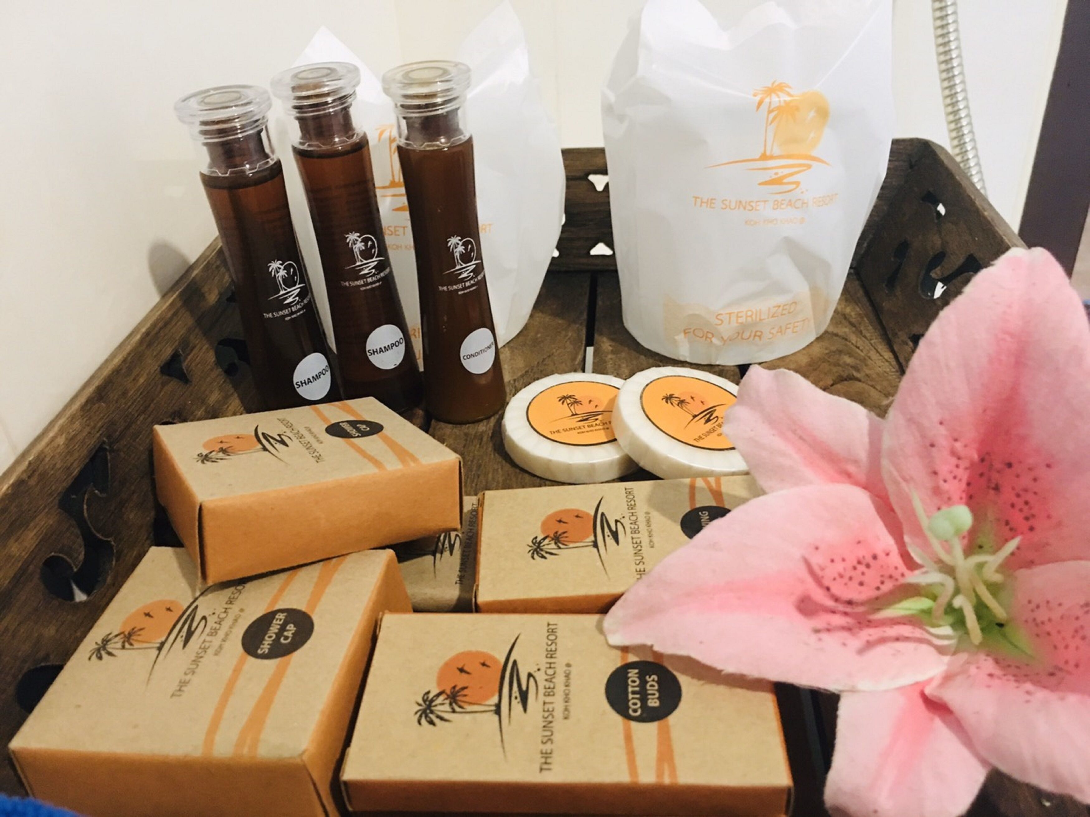 A wooden tray with various products including bottles, boxes, and a bag, likely from a resort.