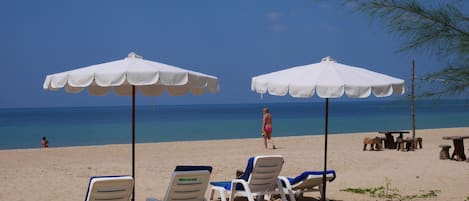 En la playa, playa de arena blanca, camastros y sombrillas