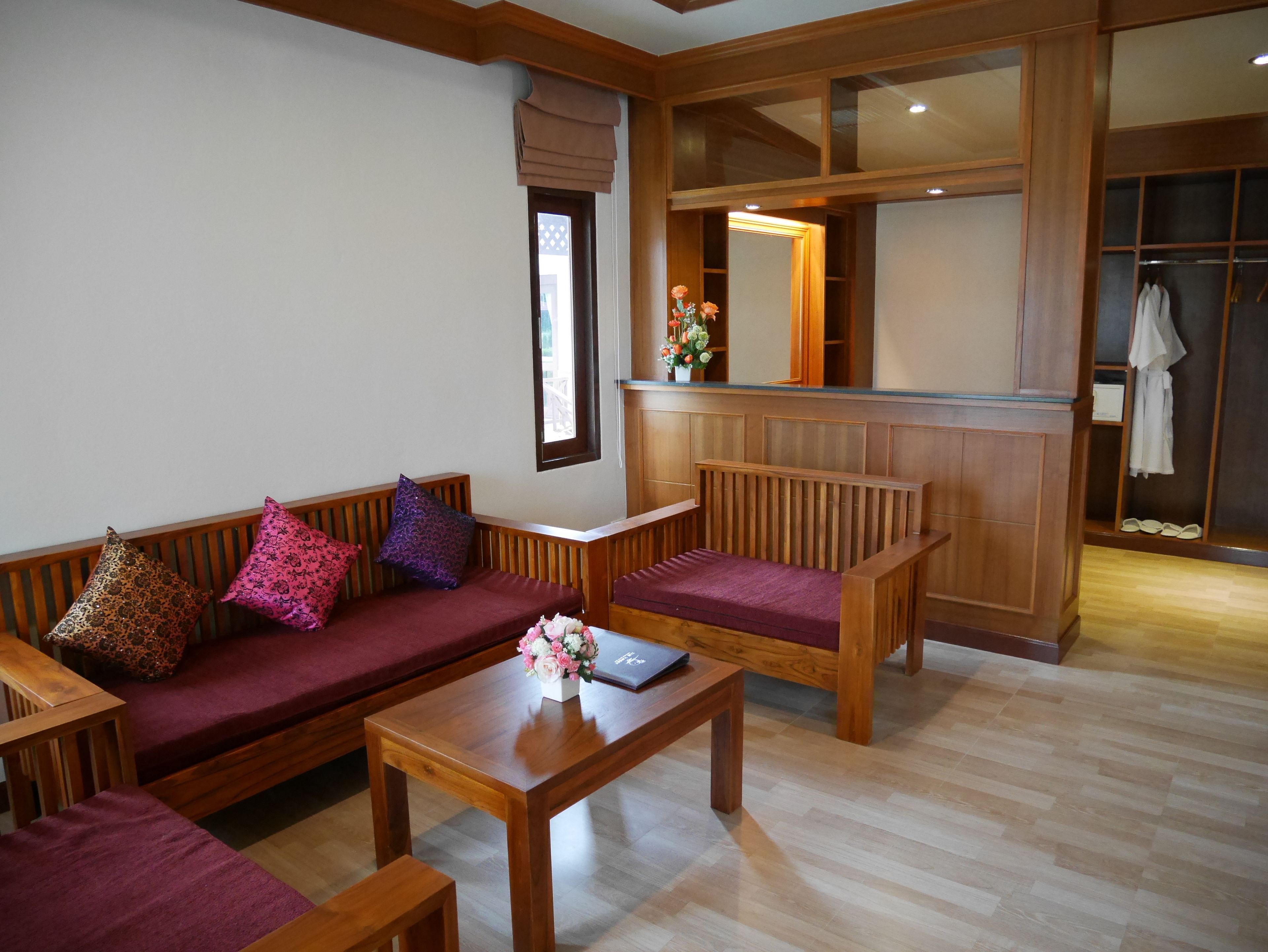 A room with a wooden bench, a wooden table, and a sofa with patterned cushions.