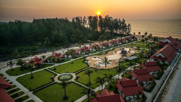 An aerial view of a resort with multiple bungalow-style buildings, a central pool area, and a beach.