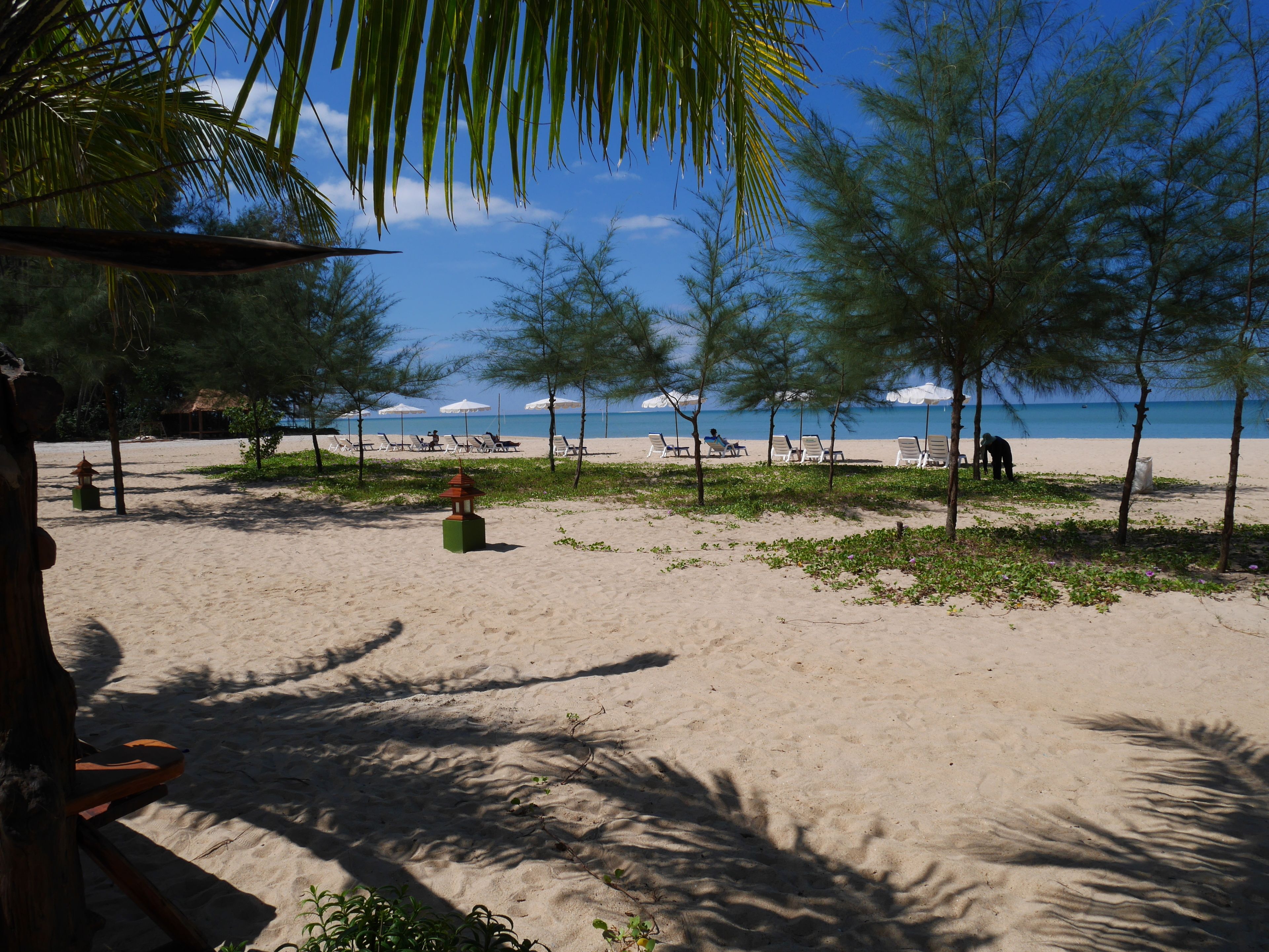 A beach with sun loungers and a small gazebo.
