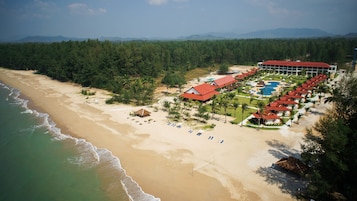 Un resort con playa, piscina y zona boscosa.