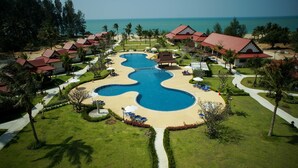 A resort with a large, winding pool, palm trees, and beach views.