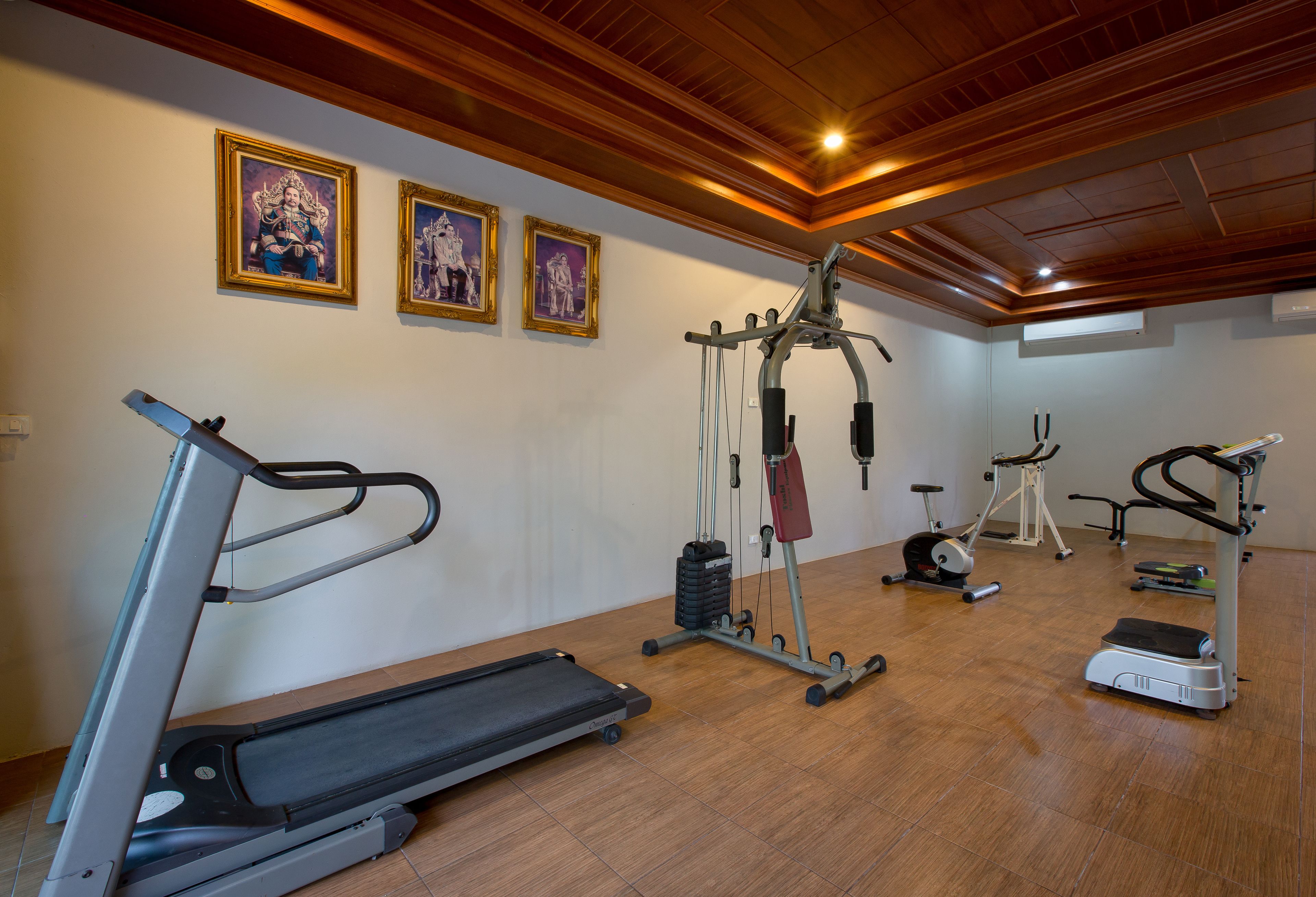 Een sportschool met loopbanden, een hometrainer en een krachttrainingapparaat.