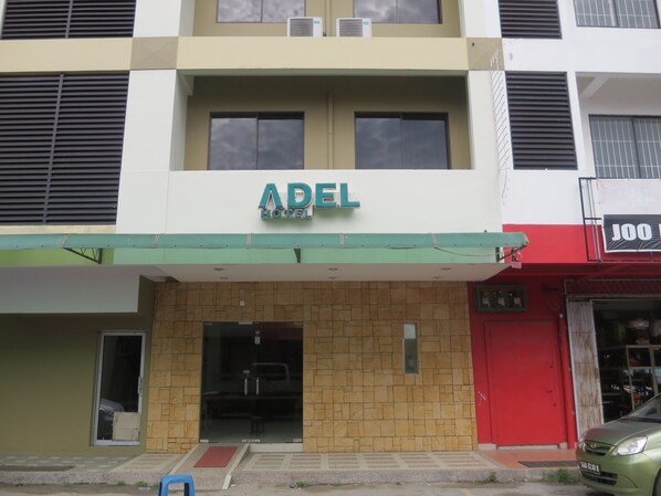 A hotel named ADEL with a green awning, a red door to the right, and a visible car parked in front. - Adel Hotel (Kota Kinabalu)