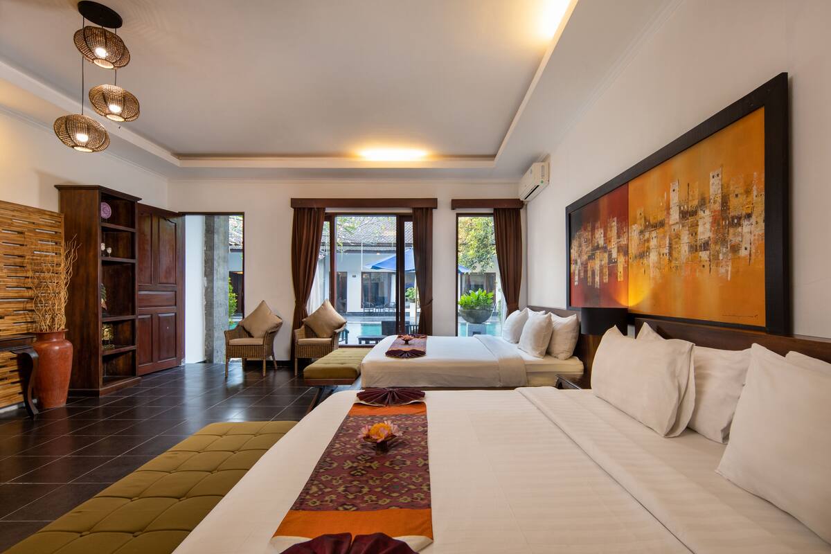 Habitación de hotel con dos camas, un cuadro grande, un sofá y vistas al exterior.