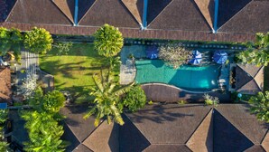 An aerial view of a resort with a swimming pool, palm trees, and a tiled roof. - Ubud Raya Boutique Hotel (Ubud)