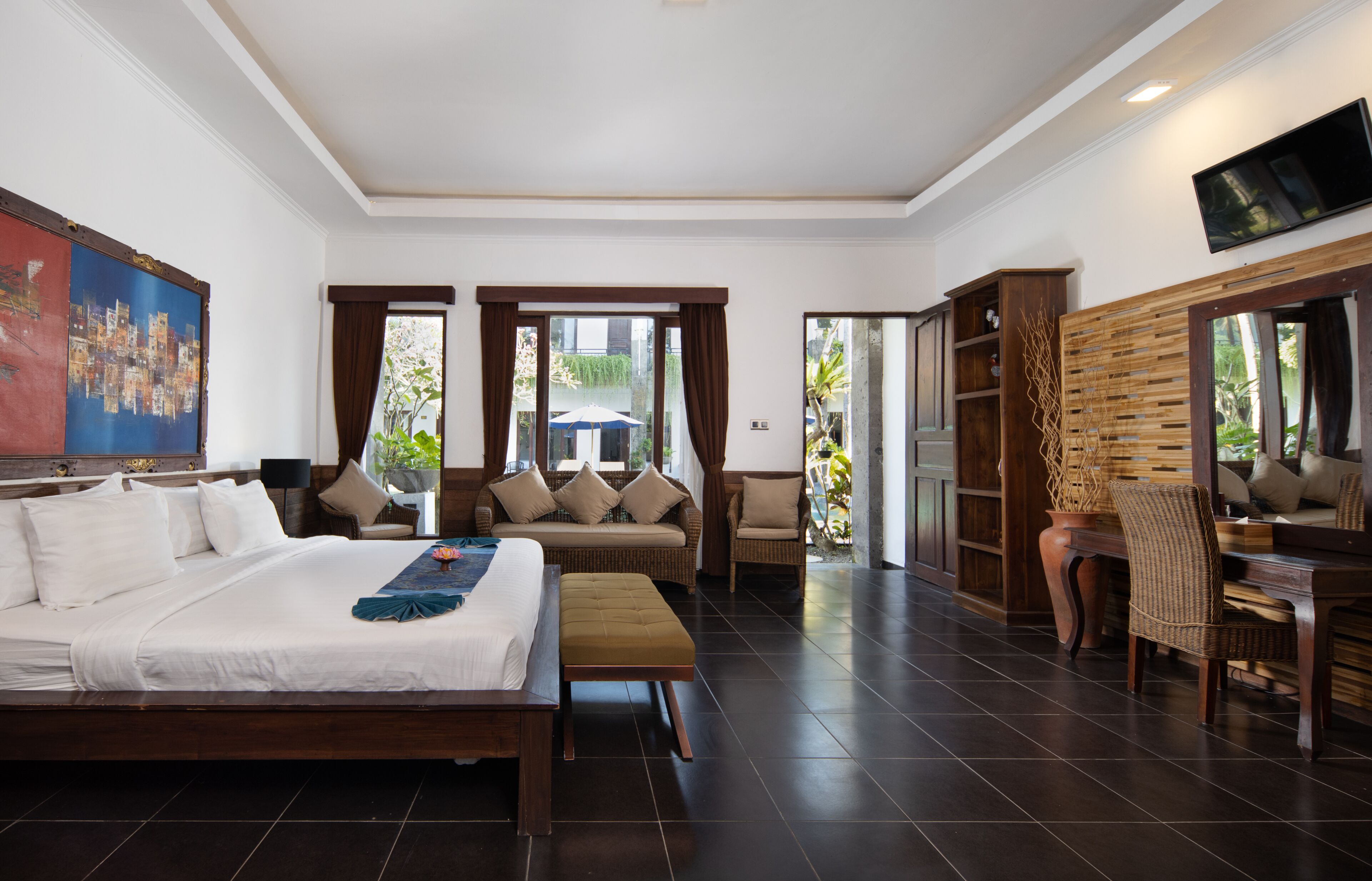 A hotel room with a large bed, a sofa, a dining table, and a TV.